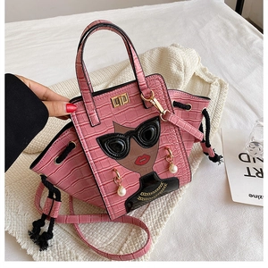 Detail of pink croc-effect handbag featuring fashion girl illustration and pearl accents