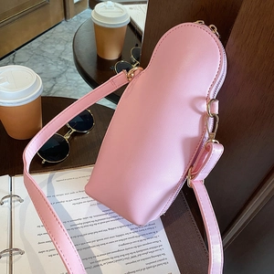 Detail of pink PU leather Russian doll bag with gold zipper and strap on a cafe table
