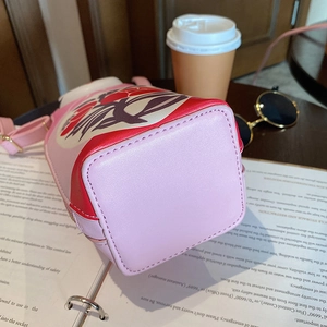 Detail of red and pink PU leather nesting doll bucket bag with floral patterns and strap