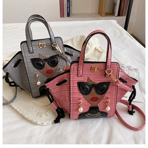 Detail of crocodile embossed wing bags in grey and pink with cartoon sunglasses lady motif