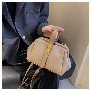 Detail of beige litchi leather shell bag with gold clasp and adjustable strap