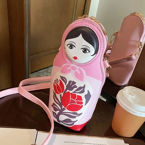 Detail of pink Russian nesting doll crossbody bag with floral patterns and gold zipper