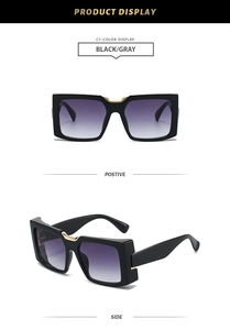 Detail of square black sunglasses showing gradient lenses and gold metal nose bridge