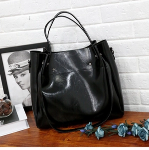 Detalle de bolso shopper negro brillante con tachuelas sobre madera y fondo de arte