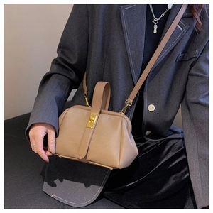 Detailed view of khaki leather shell bag with gold twist lock on a model's outfit