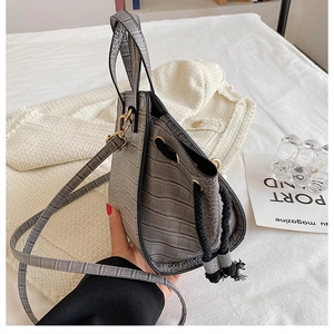 Detail of grey crocodile embossed bucket bag featuring drawstring closure and slim strap