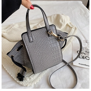 Detailed view of grey crocodile pattern handbag with drawstring and gold metal hardware