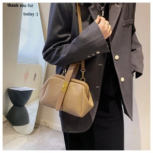 Chic beige doctor bag style handbag with golden metal clasp shown on a model