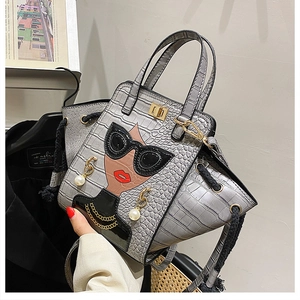 Detail of grey crocodile texture handbag with fashion graphic and pearl accessory