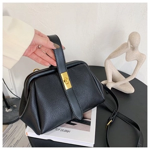 Detail of black lychee leather shell bag with gold twist lock held by a hand