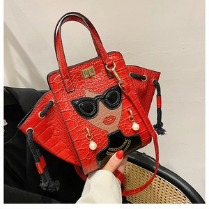 Close-up of red crocodile pattern bag with cartoon face patch and pearl earrings detail