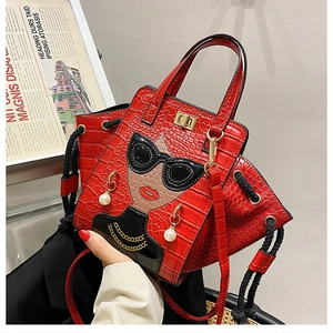 Detail of red crocodile texture handbag with cartoon portrait and pearl earring charms
