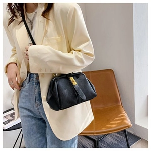 Model wearing a black lychee texture dumpling bag with a classic golden clasp lock