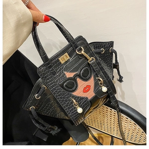Detail of crocodile embossed handbag featuring a stylish girl icon and pearl charms