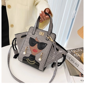 Detailed view of grey crocodile texture handbag with creative lady face and pearl earrings
