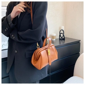 Detail of a brown leather doctor bag featuring a vintage gold clasp and textured finish