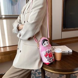 Detailed view of pink Russian nesting doll crossbody bag worn by a model in a modern room
