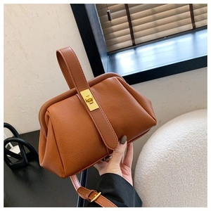 Detailed view of brown litchi grain leather shell bag with golden twist lock closure