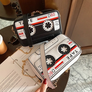 Detailed view of novelty cassette tape crossbody bag with gold chain in a cozy setting