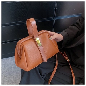 Close-up of brown litchi pattern faux leather shell bag with gold lock and wide handle