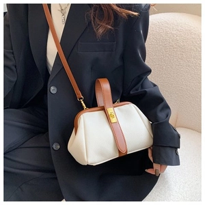 Close-up of litchi grain faux leather shell bag with gold clasp and brown handles