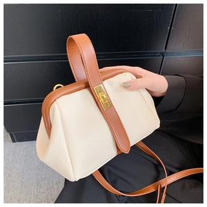 Detail of retro shell bag with cream and brown leather patchwork and metal clasp lock