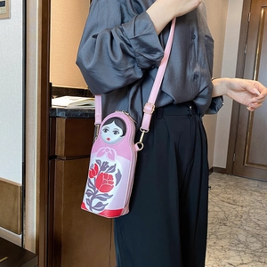 Detailed view of creative nesting doll crossbody bag with floral patterns and pink PU strap
