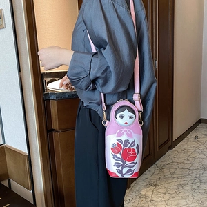 Pink Matryoshka doll crossbody bag with red floral pattern and adjustable strap