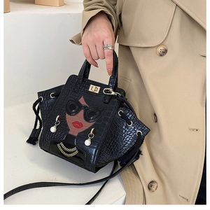 Detail of crocodile pattern handbag with sunglasses motif and pearl pendant