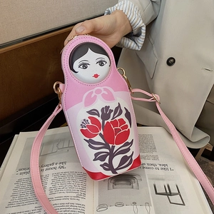 Detail of pink Russian nesting doll crossbody bag with floral prints and gold zipper