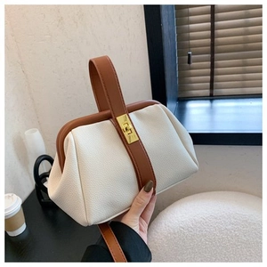 Detail of white lychee leather texture and brown handle on a shell-shaped handbag