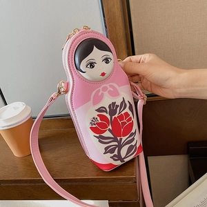 Detailed view of a pink Russian doll crossbody bag on a wooden table with café props