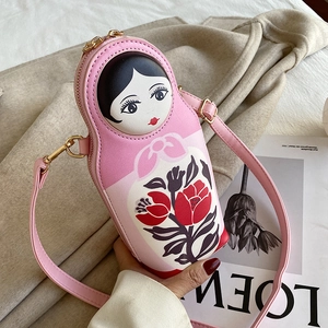 Detail of pink Russian nesting doll crossbody bag with floral patterns and gold zipper