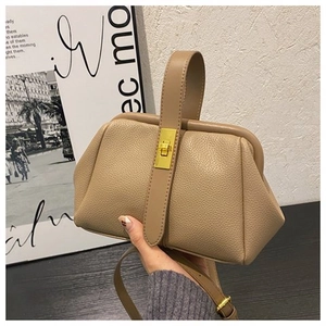 Detail of khaki pebbled leather shell bag with gold lock and sleek doctors bag structure