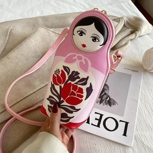 Detail of pink Russian doll shaped crossbody bag with floral print and metal zipper