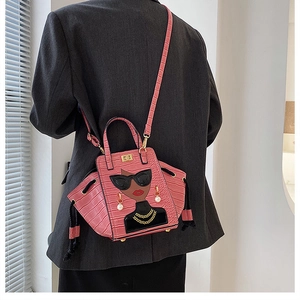 Detail of pink croc-embossed handbag with cartoon print and pearl earring detail