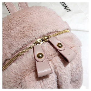 Detailed macro view of pink plush fabric and gold dual zippers with leather pulls