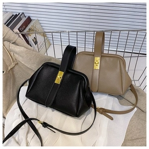 Close-up of retro doctor-style bags in black and khaki with gold metal twist locks