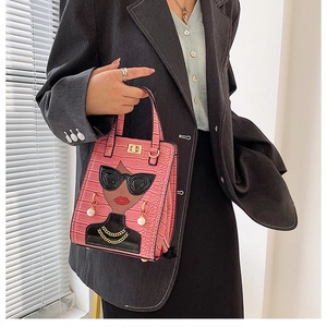 Detail of pink croc-embossed handbag featuring a fashion character with pearl accents