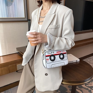 Detail showing white cassette tape cross body bag with gold chain and retro graphic prints