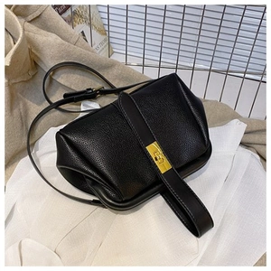 Detailed macro view of black lychee grain leather shell bag with golden metal clasp