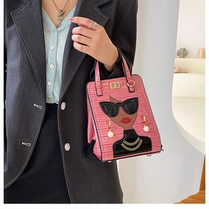 Detail of pink croc-embossed handbag with chic female cartoon applique and gold twist lock