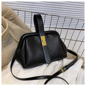 Close-up of black litchi pattern leather shell bag featuring golden clasp and hardware