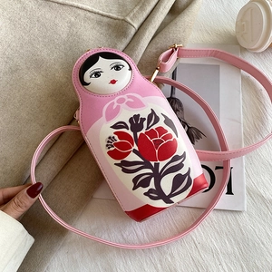 Detail of pink Russian doll crossbody bag with vintage floral prints on a textured backdrop