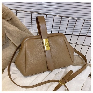 Detail of vintage brown shell bag with pebble leather texture and gold metal twist lock