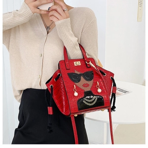 Detail of red croc-effect wing bag with cartoon character print and metal twist lock