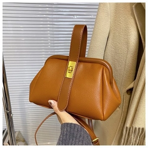 Close-up of caramel leather handbag showing pebble texture and gold metal buckle