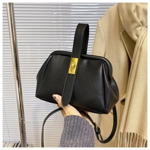 Detailed shot of black lychee leather shell bag with gold clasp and top handle