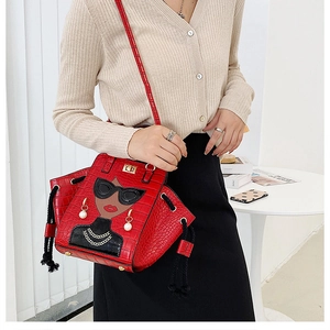 Detail of red crocodile texture handbag with unique female portrait and 3D pearl earring