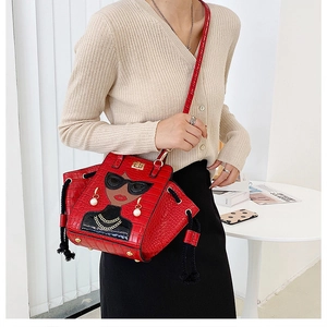 Detail of red crocodile pattern bag with cartoon female figure and pearl earrings
